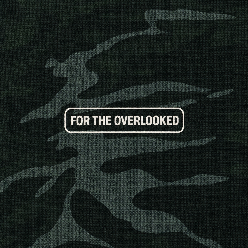 Close-up of the For the Overlooked chest label on the dark camouflage sweatshirt
